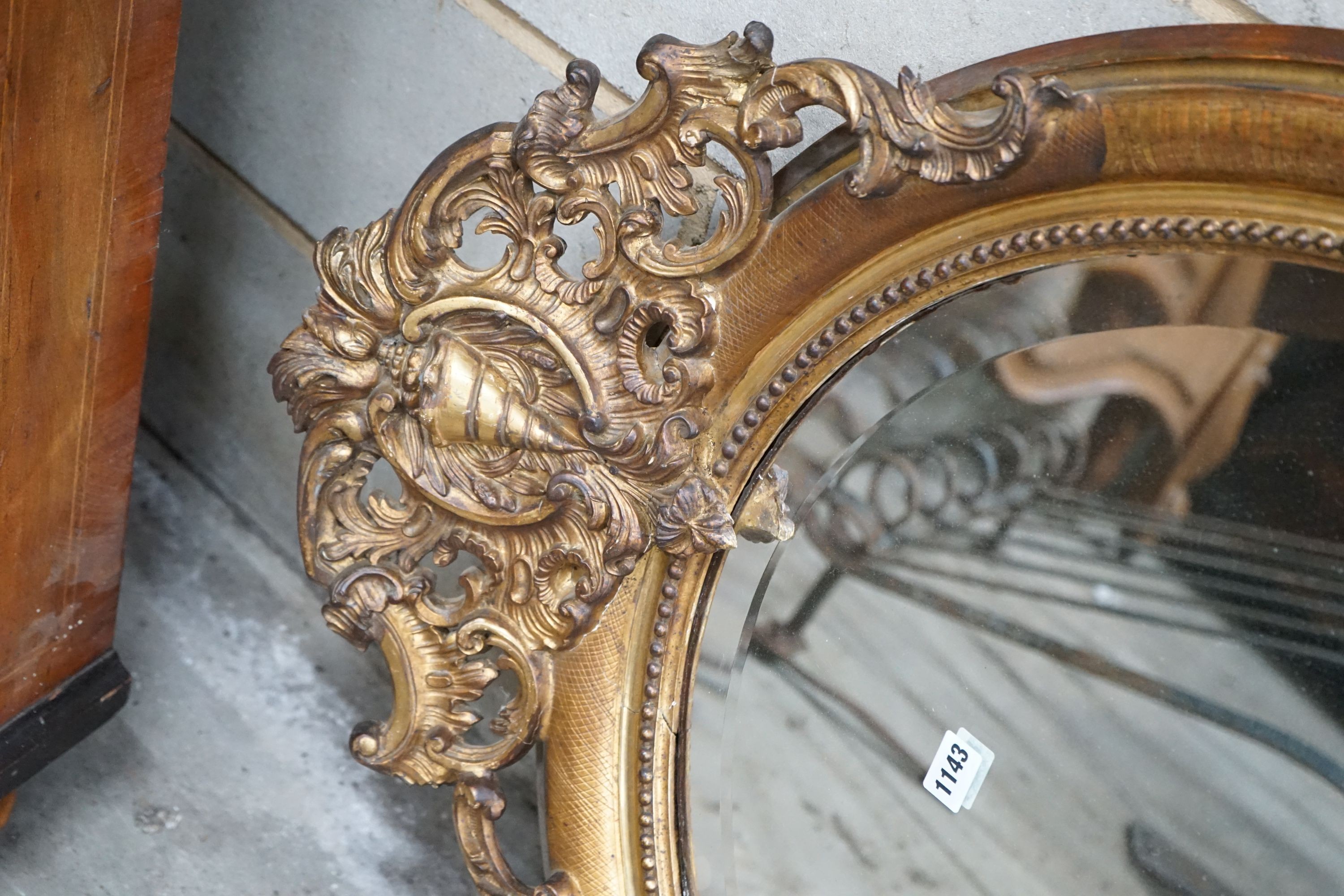 A 19th century French oval giltwood and gesso wall mirror with pierced 'C' scroll and shell pediment, width 78cm, height 118cm